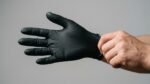 Black nitrile disposable glove being worn showing textured fingertip grip